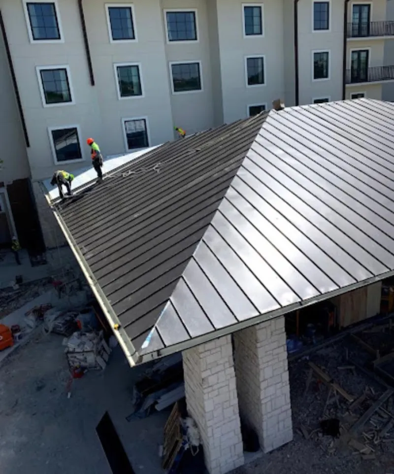 Crew installing standing seam metal roof panels on a commercial project in Germantown